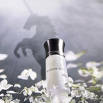 Liquides Imaginaires Blanche Bête Flakon zwischen weißen Blüten, dahinter der Schatten eines Einhorns