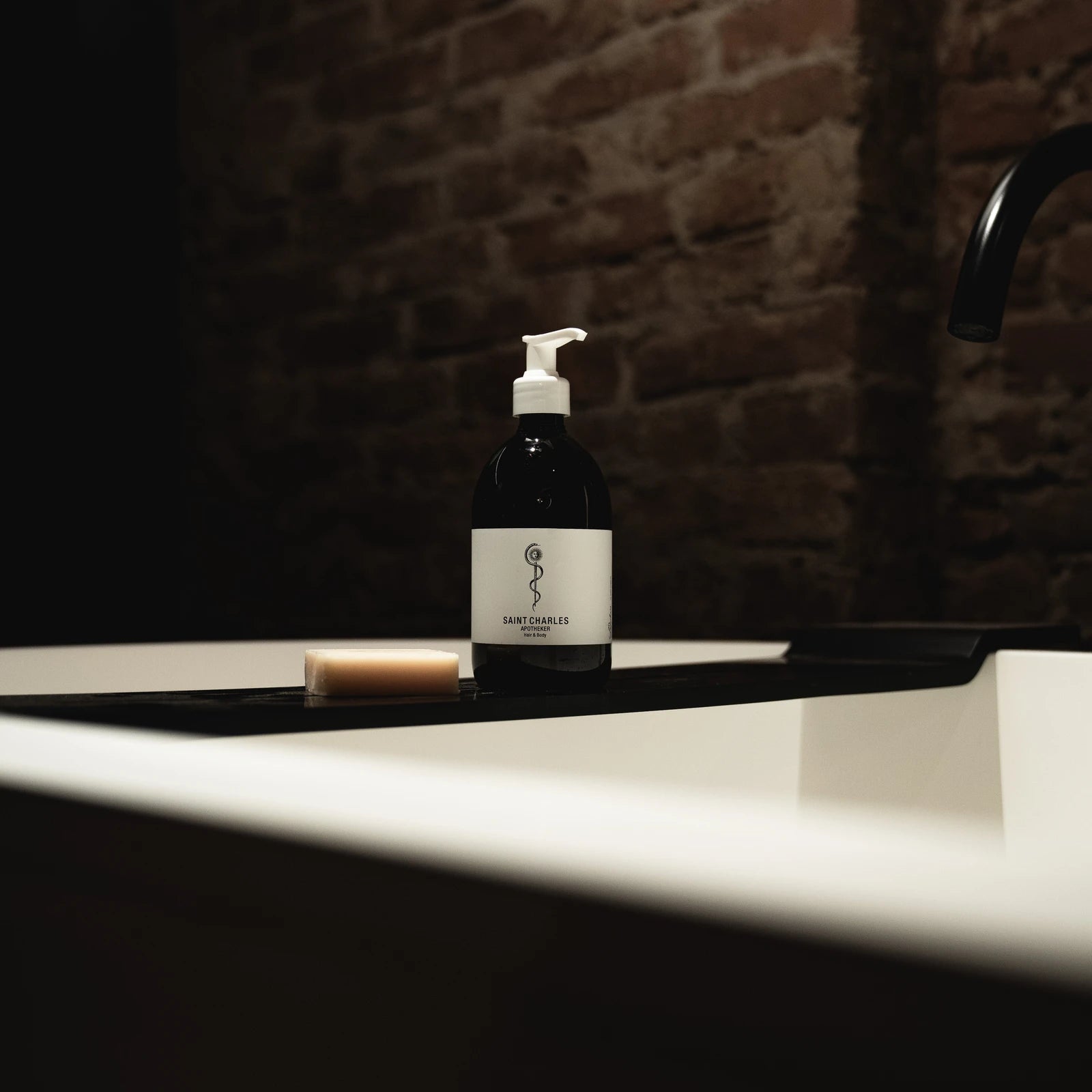 SAINT CHARLES Apotheker Hair & Body auf dem Rand einer Badewanne vor Ziegelwand
