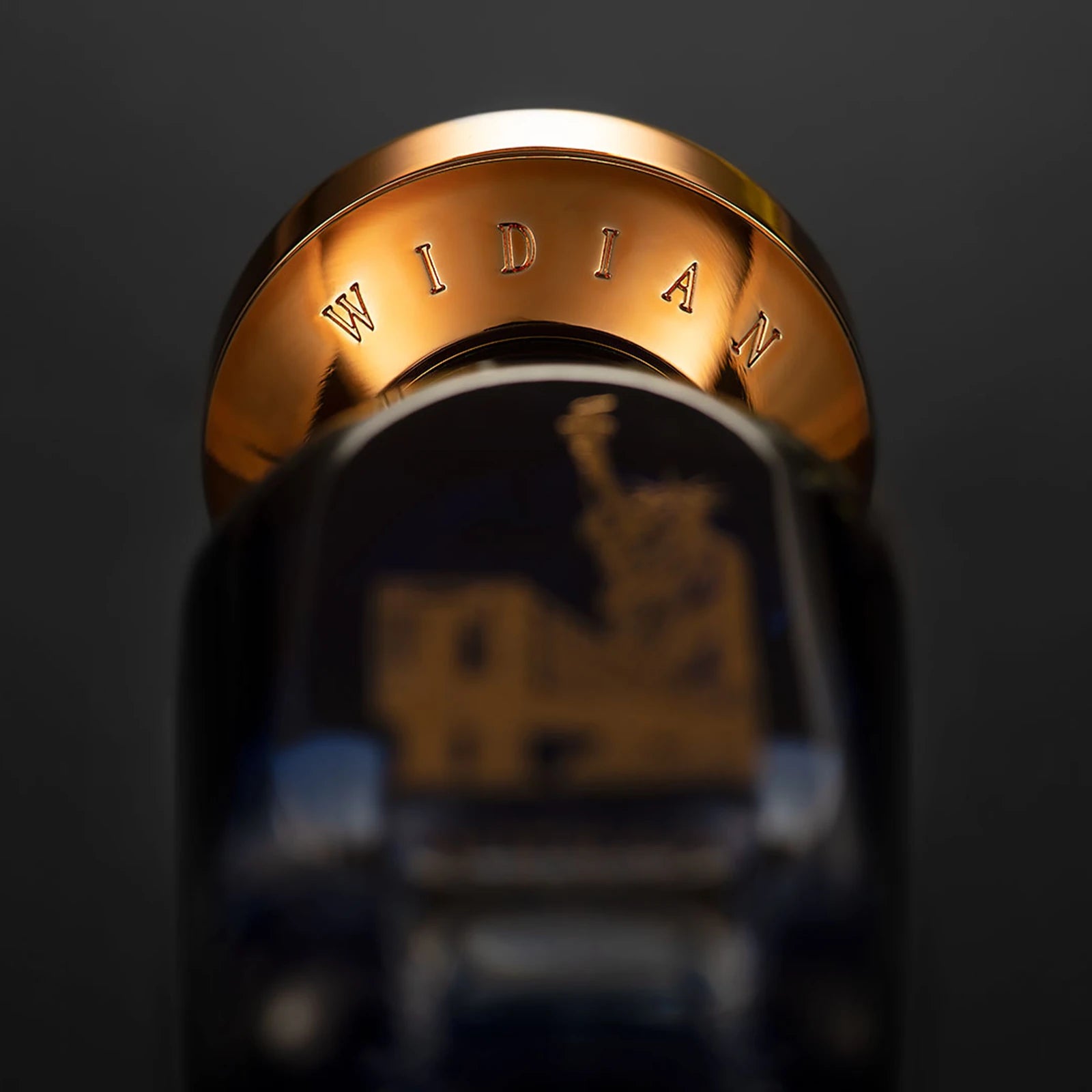 Close-up of the gold Widian cap above the New York bottle with the Statue of Liberty