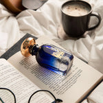Widian New York bottle on an open book beside glasses and a coffee cup
